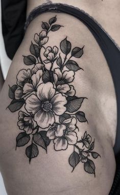 a black and white flower tattoo on the side of a woman's thigh,