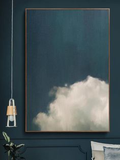 a painting hanging on the wall above a bed in a room with dark blue walls