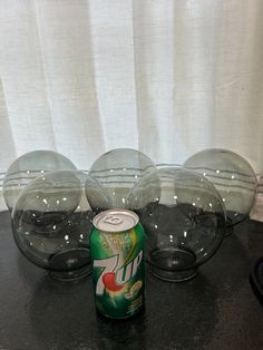 a can of soda sitting on top of a table next to glass bowls and glasses