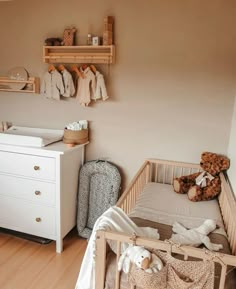 a baby's room with a crib, dresser and teddy bear on the wall