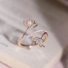 an open book with a ring on it sitting next to a pair of diamond earrings