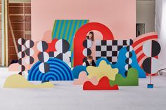 a woman is standing in front of an art installation with colorful shapes on the floor