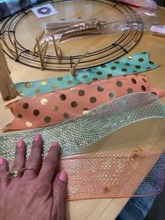 a person's hand on a table next to different colored ribbons