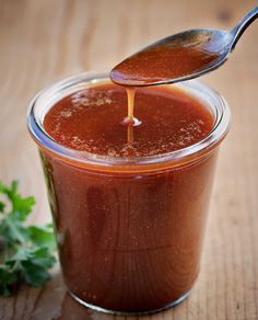 a spoon full of sauce sitting on top of a wooden table