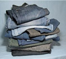 a stack of folded jeans sitting on top of a white sheet