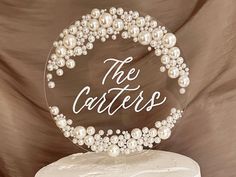 the cake is decorated with pearls, and has a name on it that reads the caterers