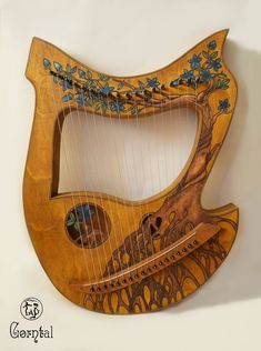 a wooden instrument with blue flowers and vines on it's sides, hanging from the wall