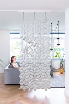 a woman sitting on a couch in front of a white wall with geometric shapes hanging from it