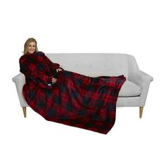 a woman is sitting on a couch wrapped in a red and black plaid flannel blanket