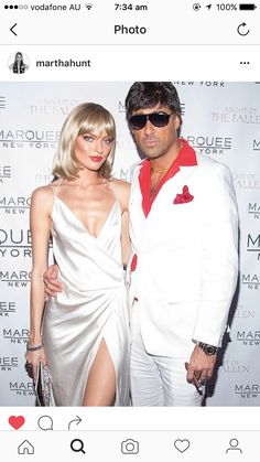 a man and woman standing next to each other in front of a white wall with the words marquee new york on it