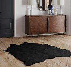 a large black rug is on the floor in front of a wooden cabinet and mirror