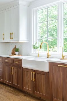 a kitchen with wooden cabinets and white counter tops, gold pulls on the faucets