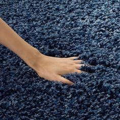 a person's hand on top of a blue rug