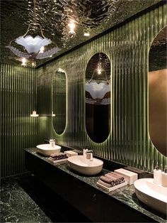 a bathroom with two sinks, mirrors and lights on the ceiling above them is green