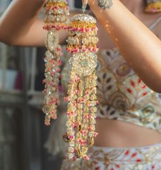 a woman in a dress is holding up some beads and bracelets that are hanging from her arm