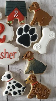 decorated cookies with dogs and numbers are on a white wooden surface, including one dog's paw