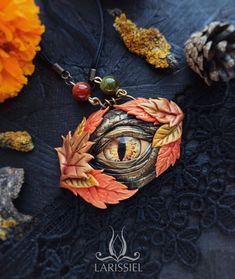 an eye is surrounded by autumn leaves and beads