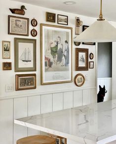 a kitchen with pictures on the wall and a stool in front of it that is underneath a lamp