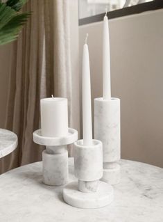 marble candlesticks are arranged on a table in front of a window