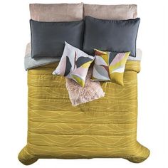 a bed with yellow sheets and pillows on it