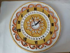 a yellow and white clock with roman numerals on the face is sitting on a piece of paper