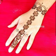 a woman's hand with henna tattoos on her left hand and flowers on the wrist