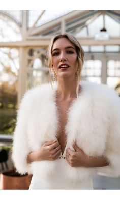 a woman in a white dress and fur coat