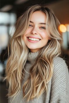 A natural cool wheat blonde base mixes with soft, light brown undertones. This creates an inviting look that's both understated and versatile, complementing the gentle waves for a seamless, sunkissed style. Click here to see more blond hair color ideas. Blonde Hair Transformations