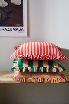 three pillows stacked on top of each other in front of a framed photo and white roses