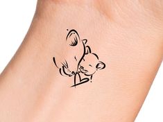 a small tattoo on the wrist of a woman's arm with a bear holding a heart