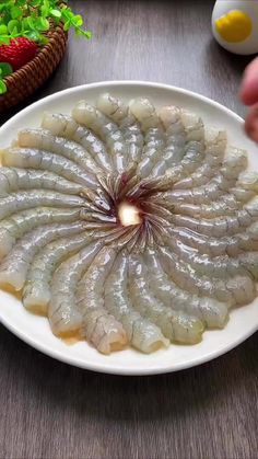 a white plate topped with shrimp on top of a wooden table