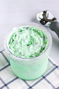 a cup filled with green cream sitting on top of a checkered table cloth