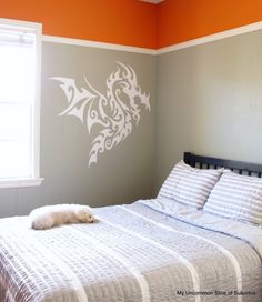 a bed sitting under a window next to a wall with a dragon decal on it