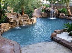 an outdoor pool with waterfall and rocks