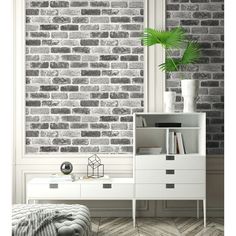 a white dresser sitting in front of a window next to a brick wall with a potted plant on top