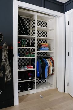 an organized closet with checkered walls and white shelves