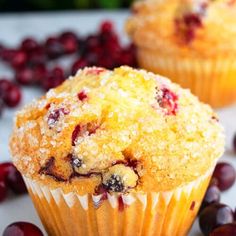 two cranberry muffins sitting on top of a white table next to some berries