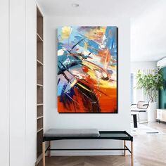 an abstract painting hangs on the wall above a bench