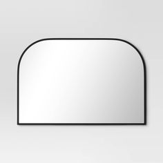 an oval mirror with black frame on a white wall, reflecting the light from below