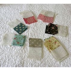 several pieces of cloth laid out on top of a white bed spread with different patterns and colors