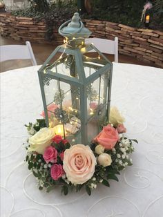 a table with a lantern and flowers on it, lit up by fairy lights at the top