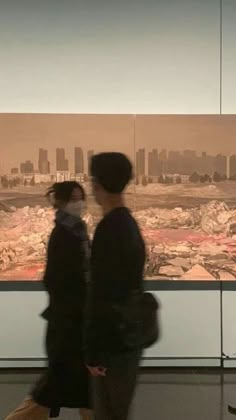 two people are walking in front of a painting