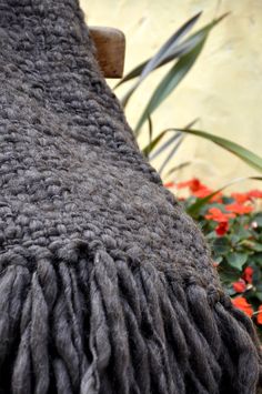 a close up view of the back end of a bench with flowers in the background