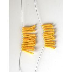 three pieces of yellow corn on a white surface with string attached to them and two strings connected