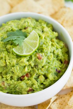 guacamole and tortilla chips on a plate with lime wedges