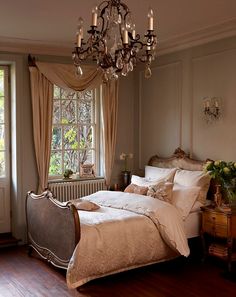 a bedroom with a chandelier hanging from the ceiling next to a large bed