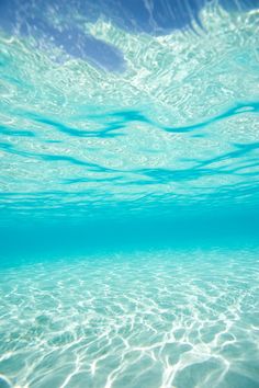 an underwater view of the ocean with clear water and blue sky in the back ground