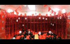 balloons and streamers are hanging from the ceiling in a room with red curtained walls