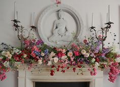 a mantel decorated with flowers and candles