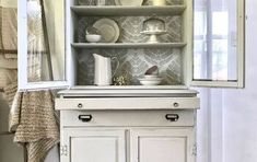 a white cabinet with dishes on it in a room